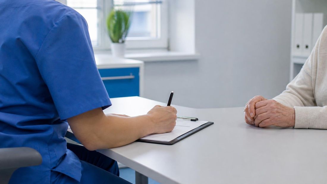 Medicinska sestra bilježi podatke na obrazac tijekom mirnoga razgovora s bolesnikom prije procjene kronične rane; prikazane su samo ruke, bez rane i bez prepoznatljivih osoba.