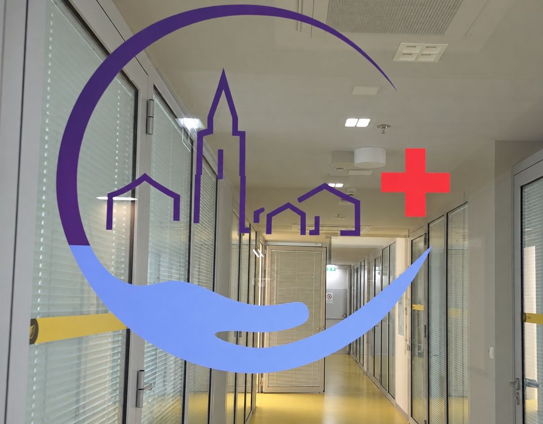 Znak Simulacijskog centra Zadar: obrisi zvonika i kuća s crvenim križem iznad ruke, na staklu hodnika centra